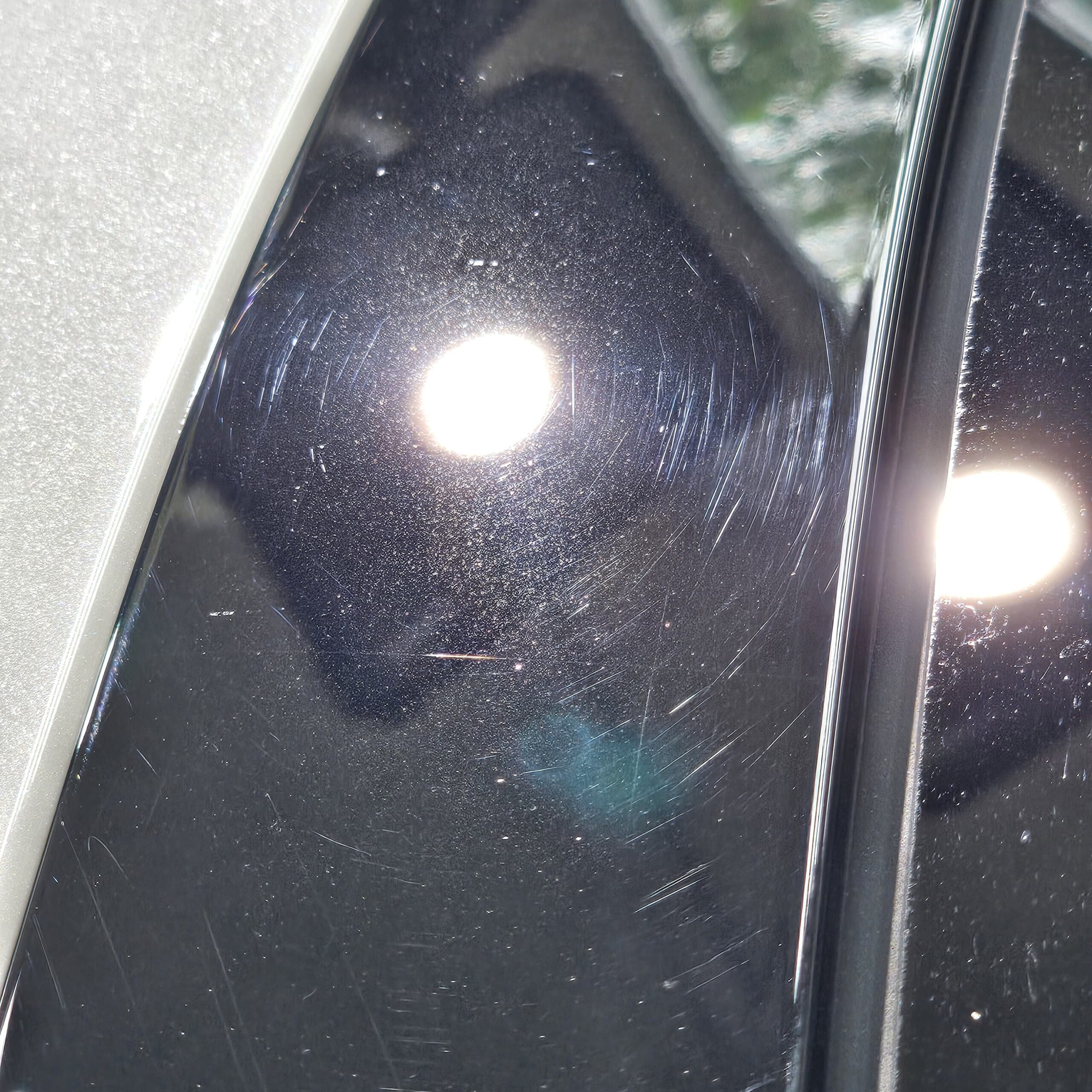 Same black panel under same inspection light after multi-stage paint correction with all swirl marks and scratches removed