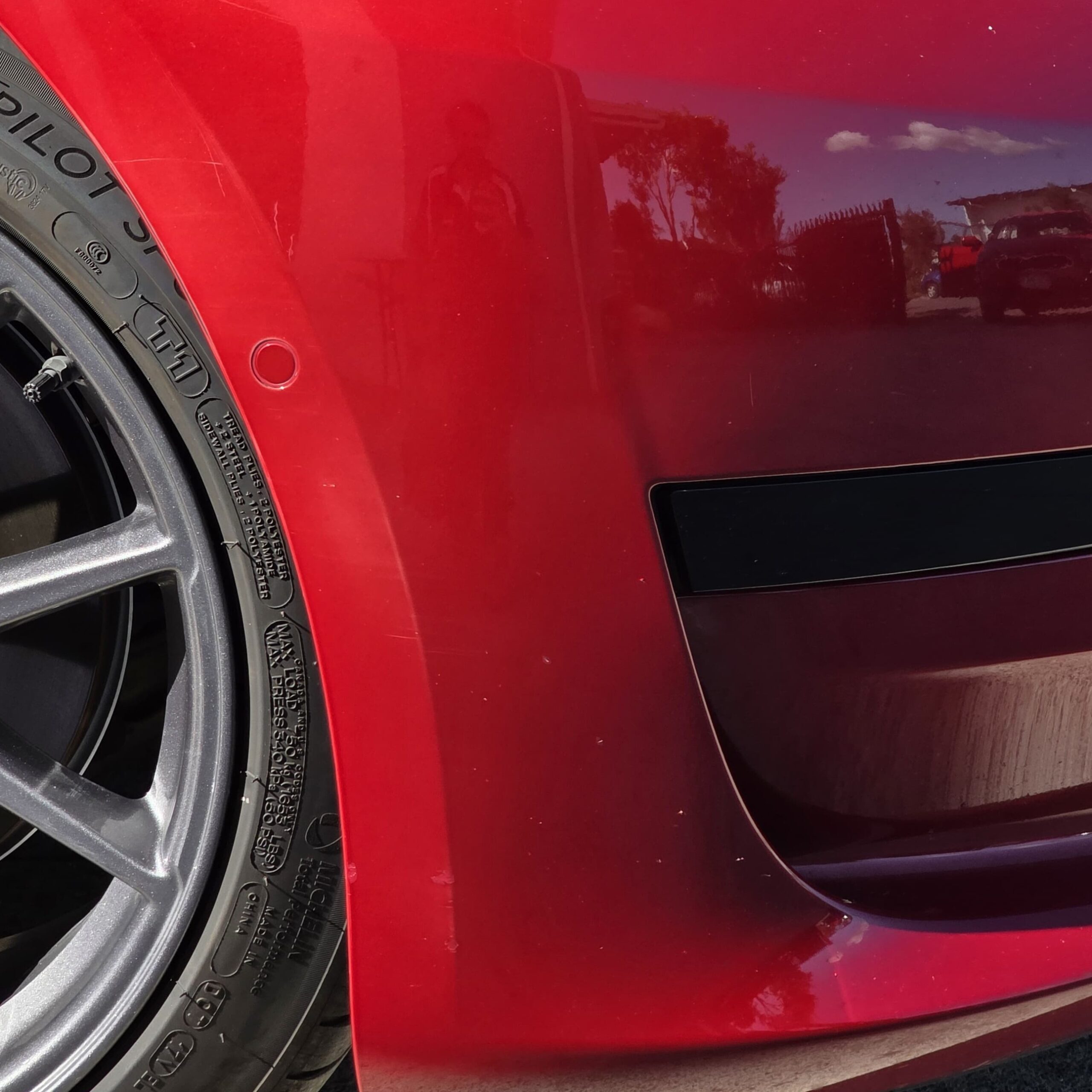 Tesla Model 3 in red metallic with white scuff transfer and deep scratches on front quarter panel before paint correction at JETWASH Coolum Beach