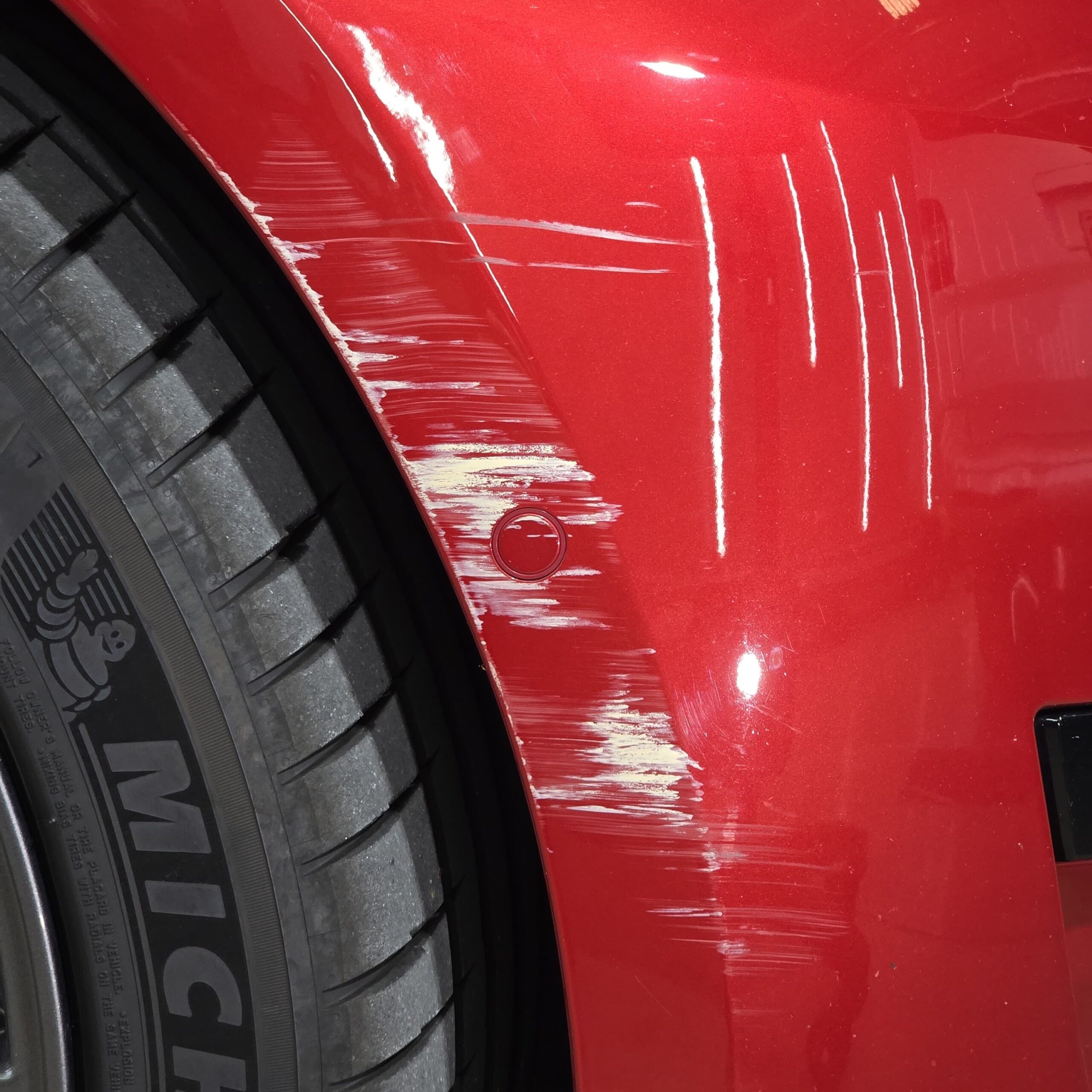 Same Tesla Model 3 front quarter panel after multi-stage paint correction showing flawless red paint with mirror reflection